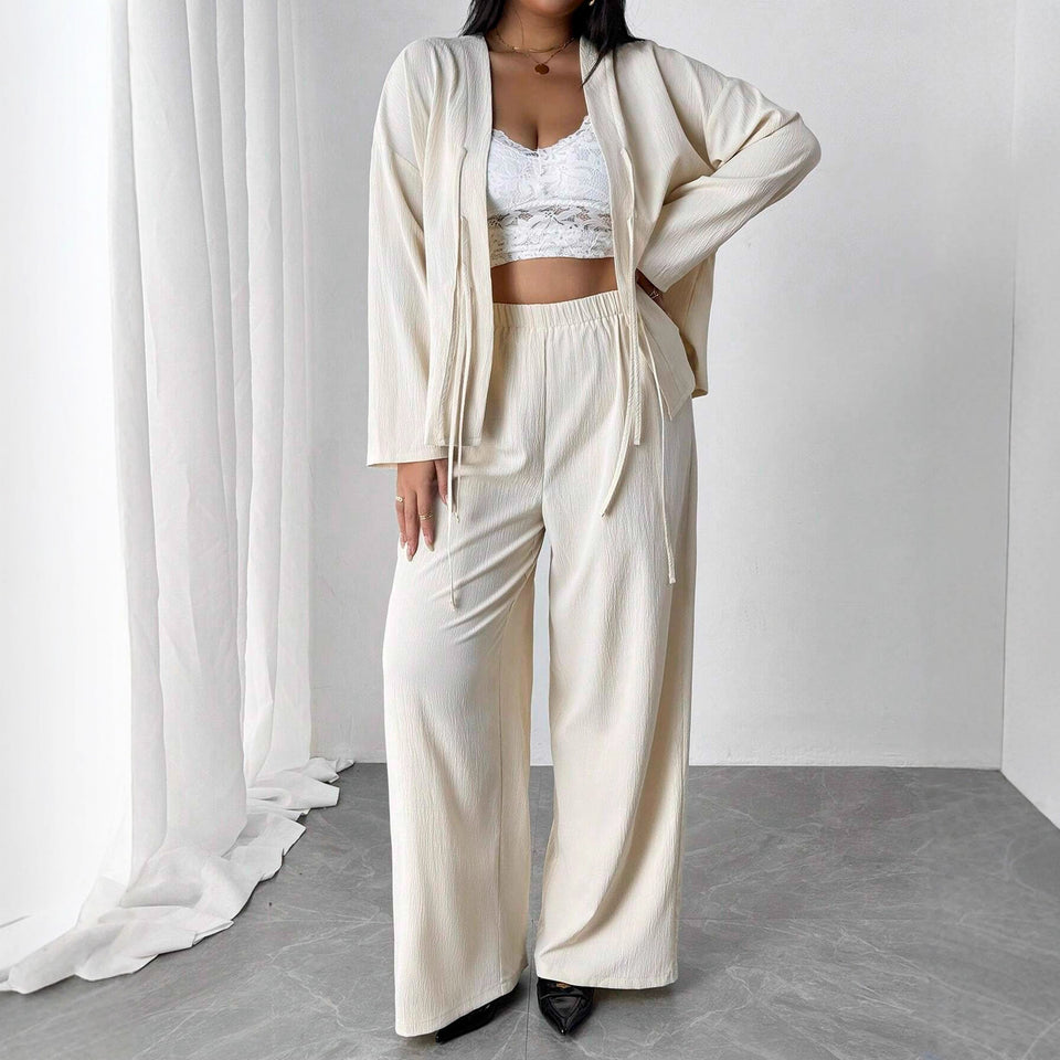 Person wearing a white outfit with a cardigan in a minimalistic setting