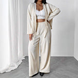 Person wearing a white outfit with a cardigan in a minimalistic setting
