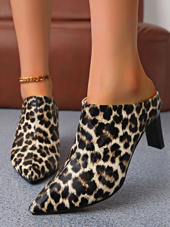 Leopard print high-heeled shoes worn by a person on a neutral background