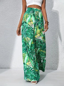 Green leaf-patterned pants worn by a person on a gray background
