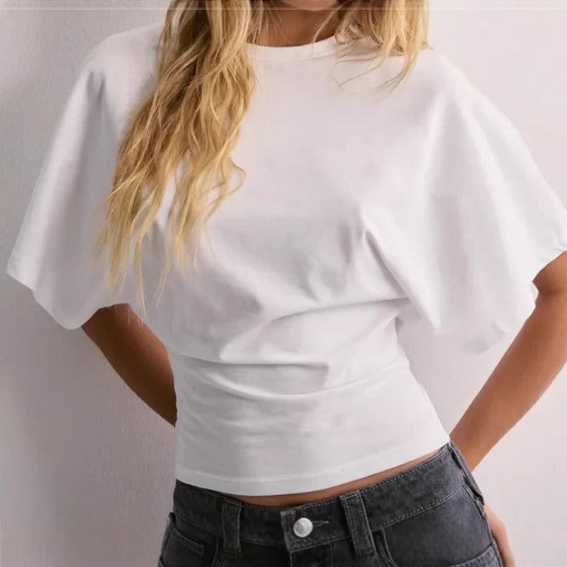 Person wearing a white crop top and black jeans against a plain background