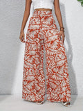 Person wearing red and white leaf-patterned wide-leg pants on a neutral background
