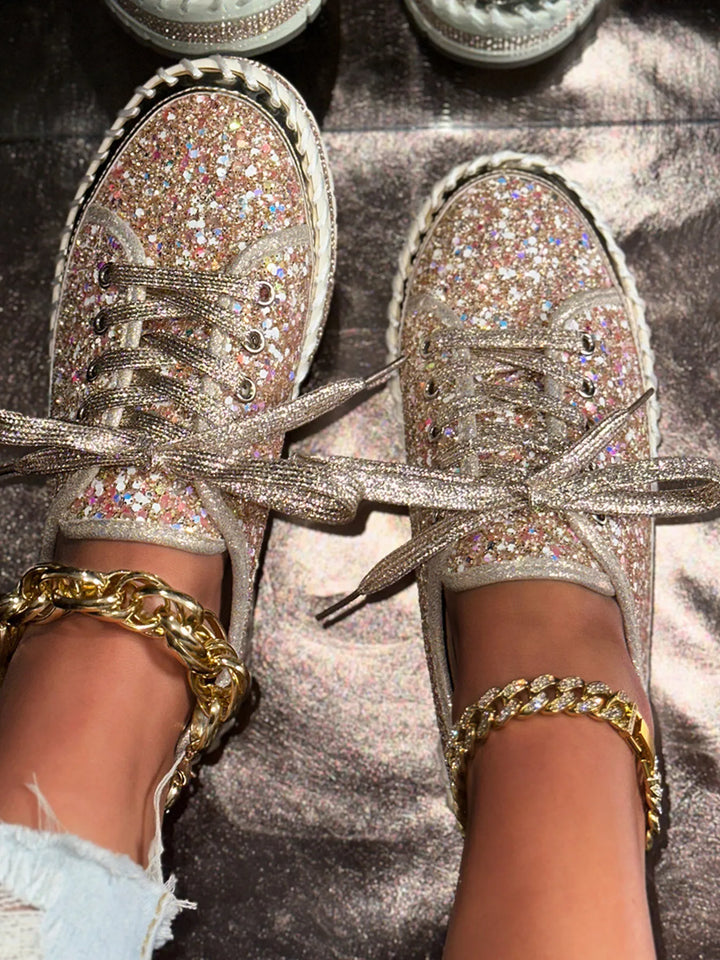 Glittery sneakers with gold chains and bracelets on a reflective surface