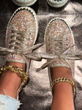 Glittery sneakers with gold chains and bracelets on a reflective surface