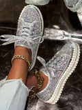 Silver glittery sneakers with rhinestone details on a dark surface.