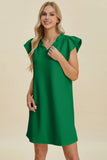 Woman wearing a green dress against a beige background