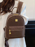 Brown backpack with gold accents worn by a person against a neutral background