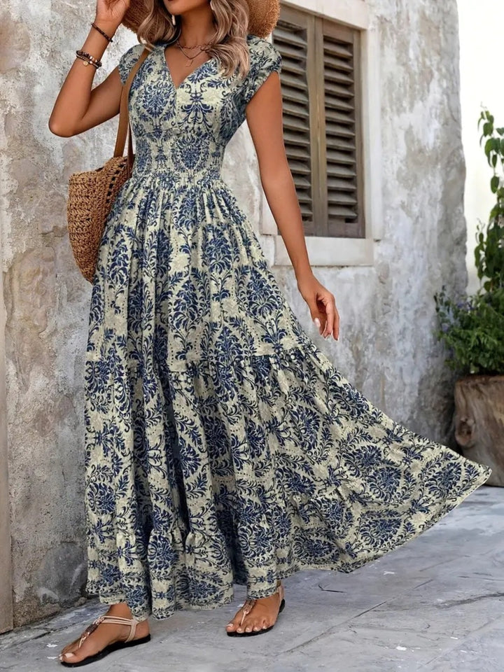 Woman wearing a floral dress standing against a stone wall.