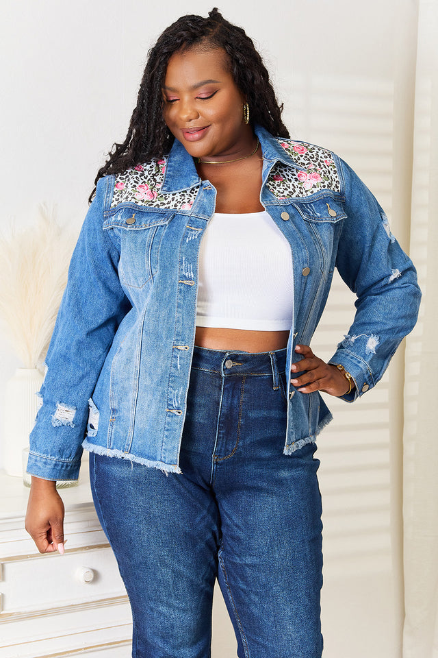 Woman wearing a denim jacket with floral embroidery and high-waisted jeans.