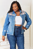 Woman wearing a denim jacket with floral embroidery and high-waisted jeans.