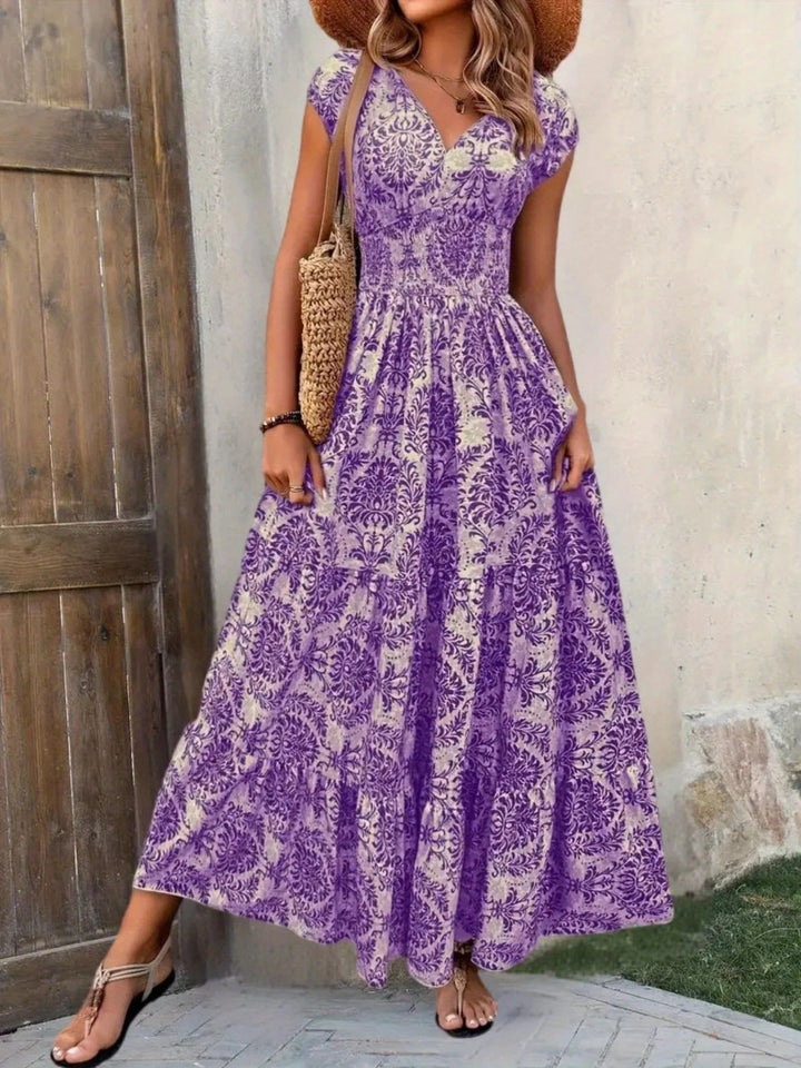 Woman wearing a purple floral dress standing against a wooden door and concrete wall.