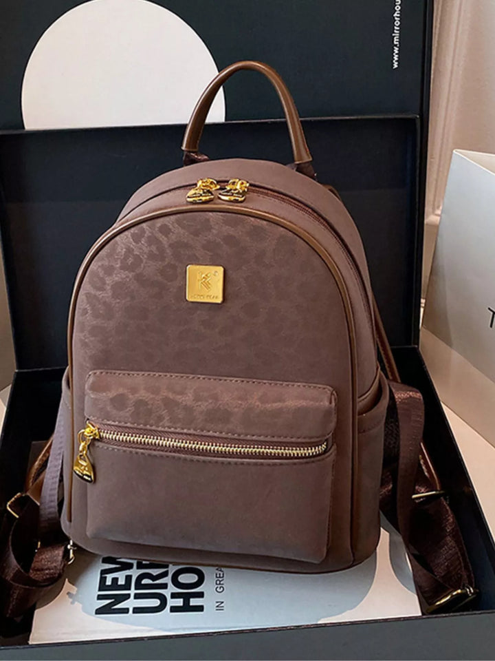 Brown backpack with gold accents on a black surface