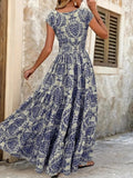 Woman wearing a blue floral dress standing against a stone wall.