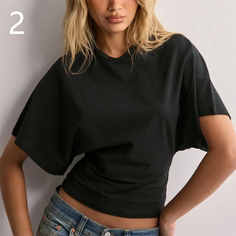 Person wearing a black crop top and blue jeans against a plain background