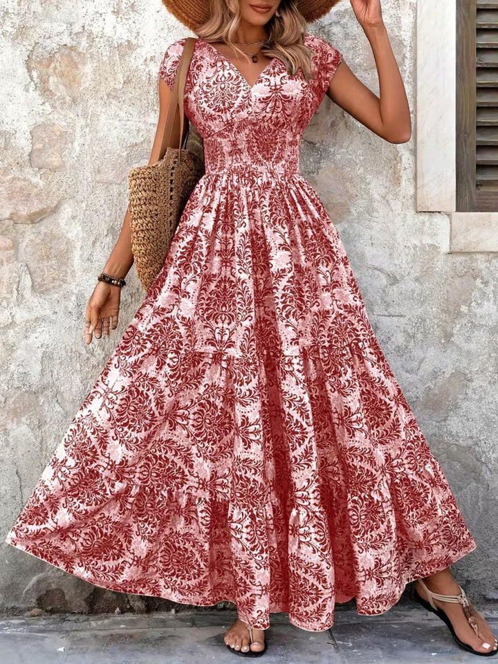 Woman wearing a red floral dress standing against a stone wall.