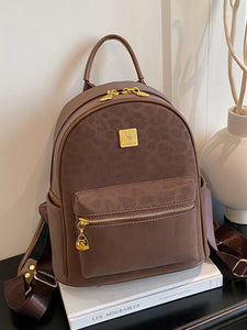 Brown backpack with gold accents on a white surface