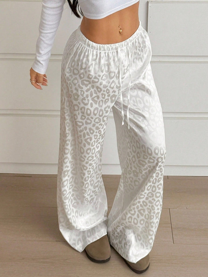 White leopard print pants worn by a person on a wooden floor.
