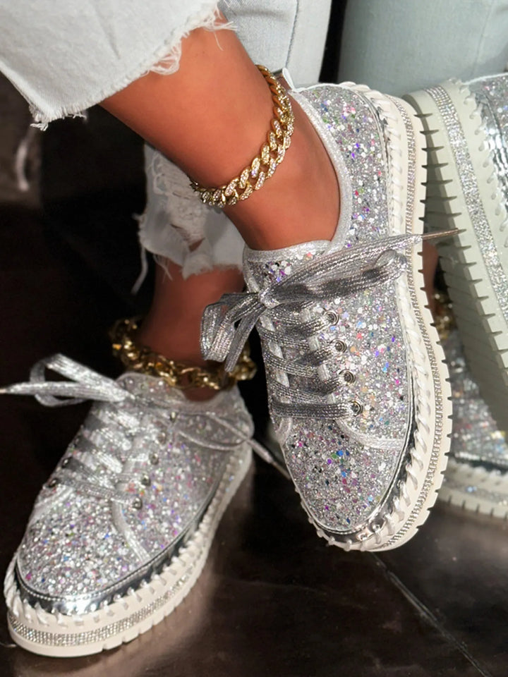 Silver glittery sneakers with a platform sole worn indoors.