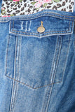 Close-up of a blue denim pocket with a floral and leopard print fabric background