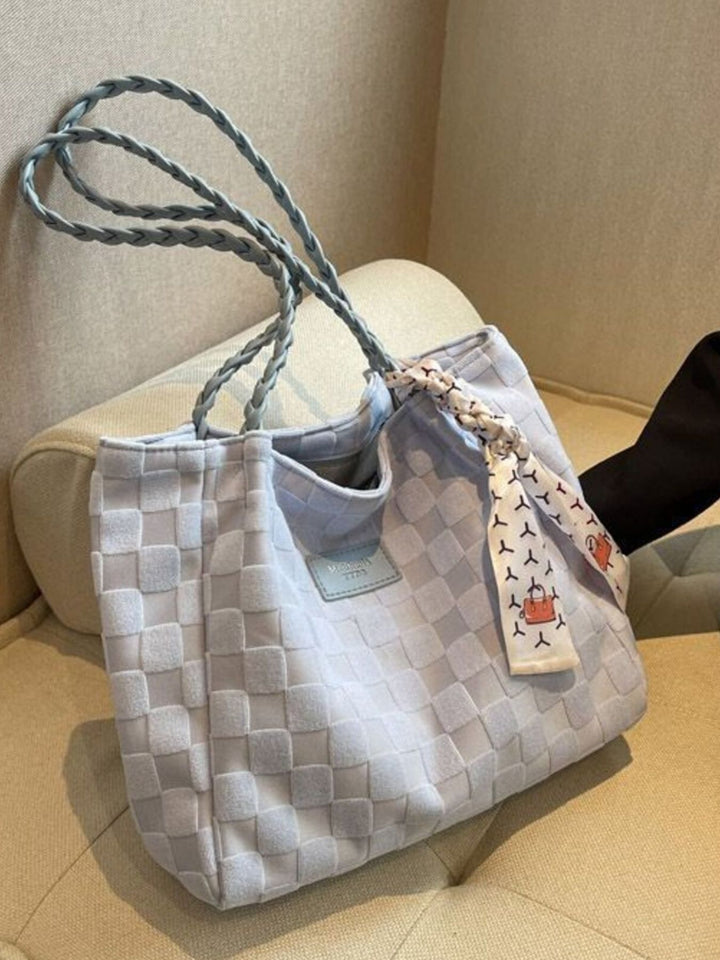 Woven handbag with a decorative tag on a beige surface
