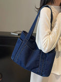 Person holding a blue denim tote bag with a neutral background