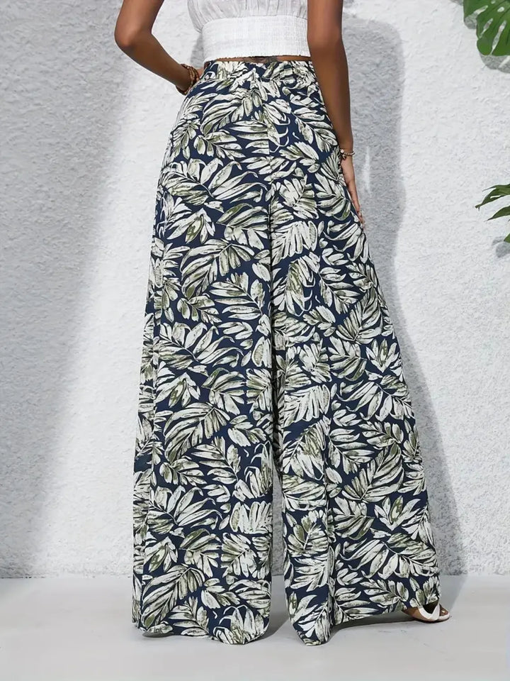 Tropical leaf patterned pants worn by a person on a light gray background