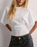 Person wearing a white crop top and black jeans against a plain background