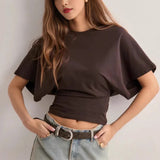 Person wearing a brown crop top and light blue jeans against a plain background