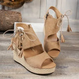 Beige wedge sandals with raffia details on a wooden floor.
