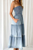 Woman wearing a strapless denim dress against a white curtain background
