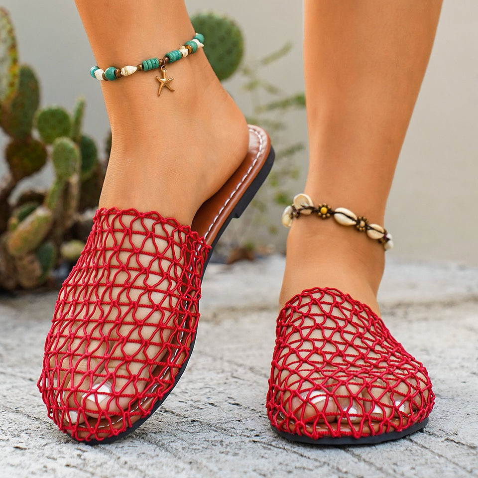 Red woven sandals worn with a blurred cactus plant background