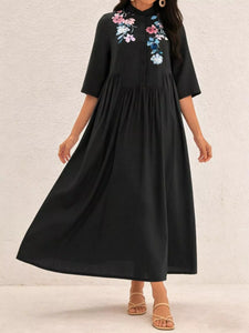 Black dress with floral embroidery on a plain background