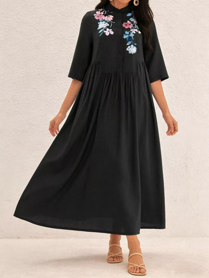 Black dress with floral embroidery on a plain background